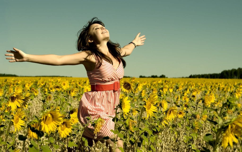 woman with her arms open in sunflower field
